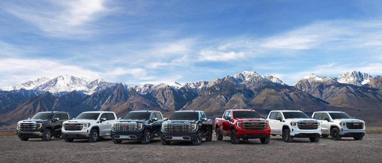 GMC trucks lined up in front of mountains