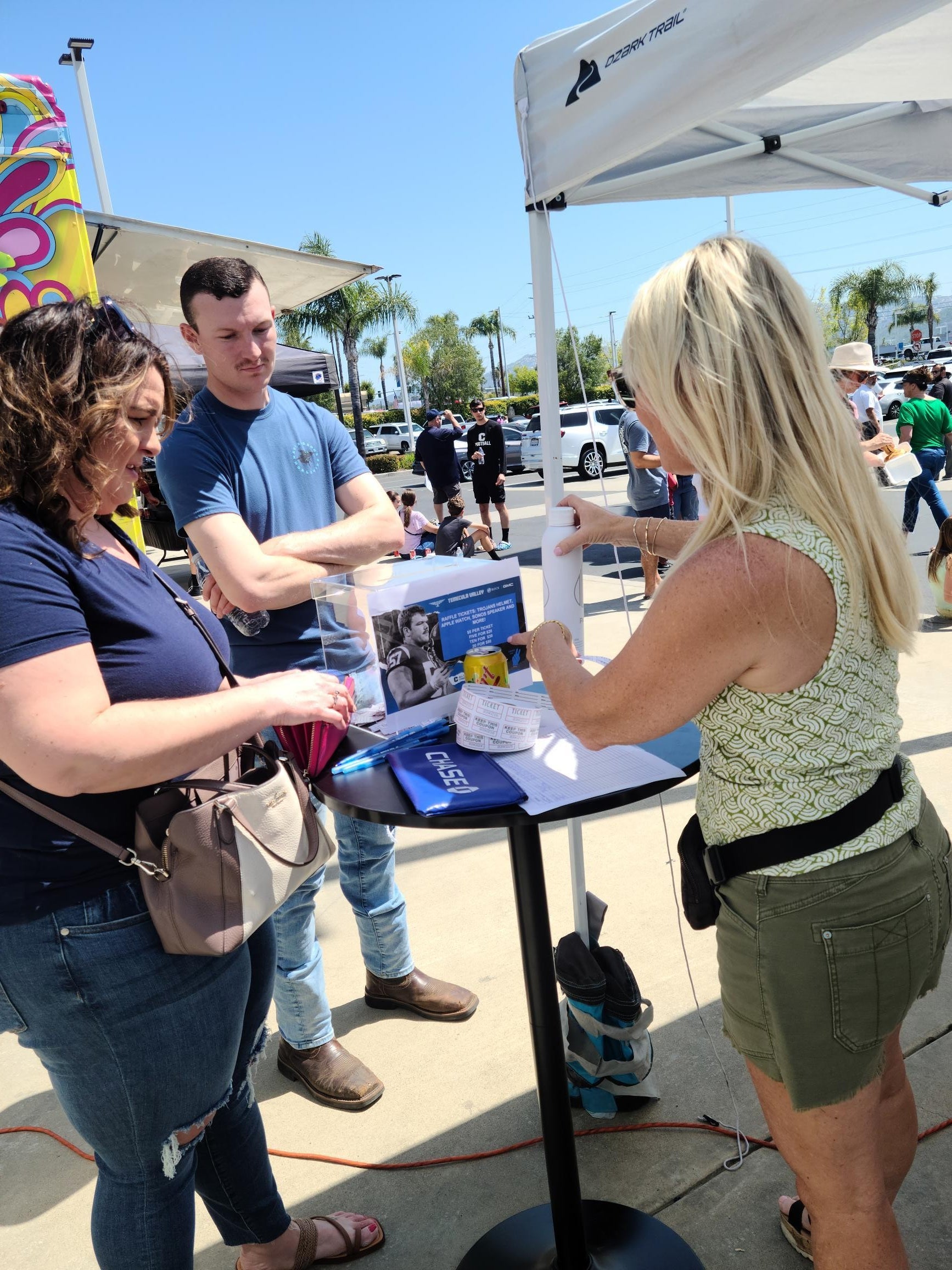 People standing at a raffle ticket table at the USC Chapparal Football Event
